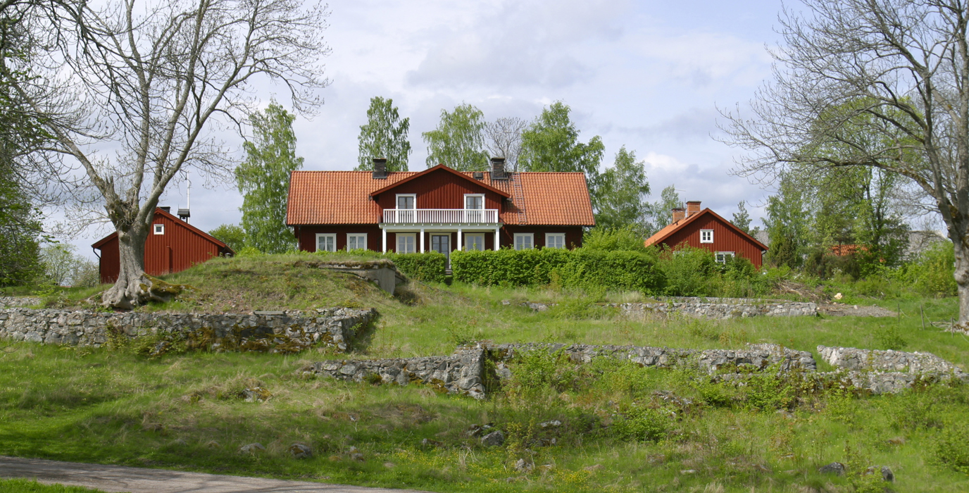Kungsbergs mangårdsbyggnad med flyglar. I backen framför gården syns resterna av Vårfruberga klosterruin. Vår och grönska.